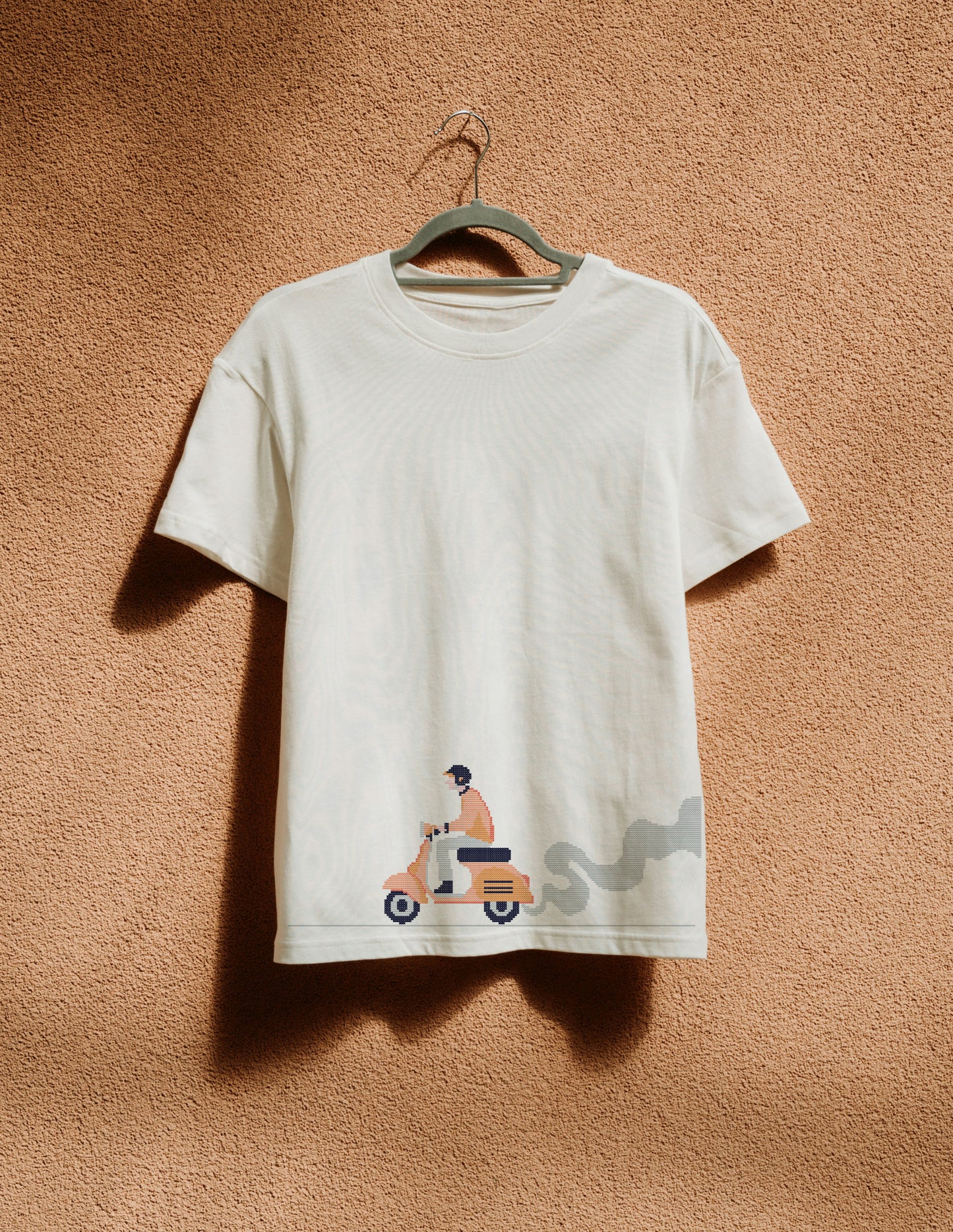 White t-shirt with graphic design on a hanger against a beige wall