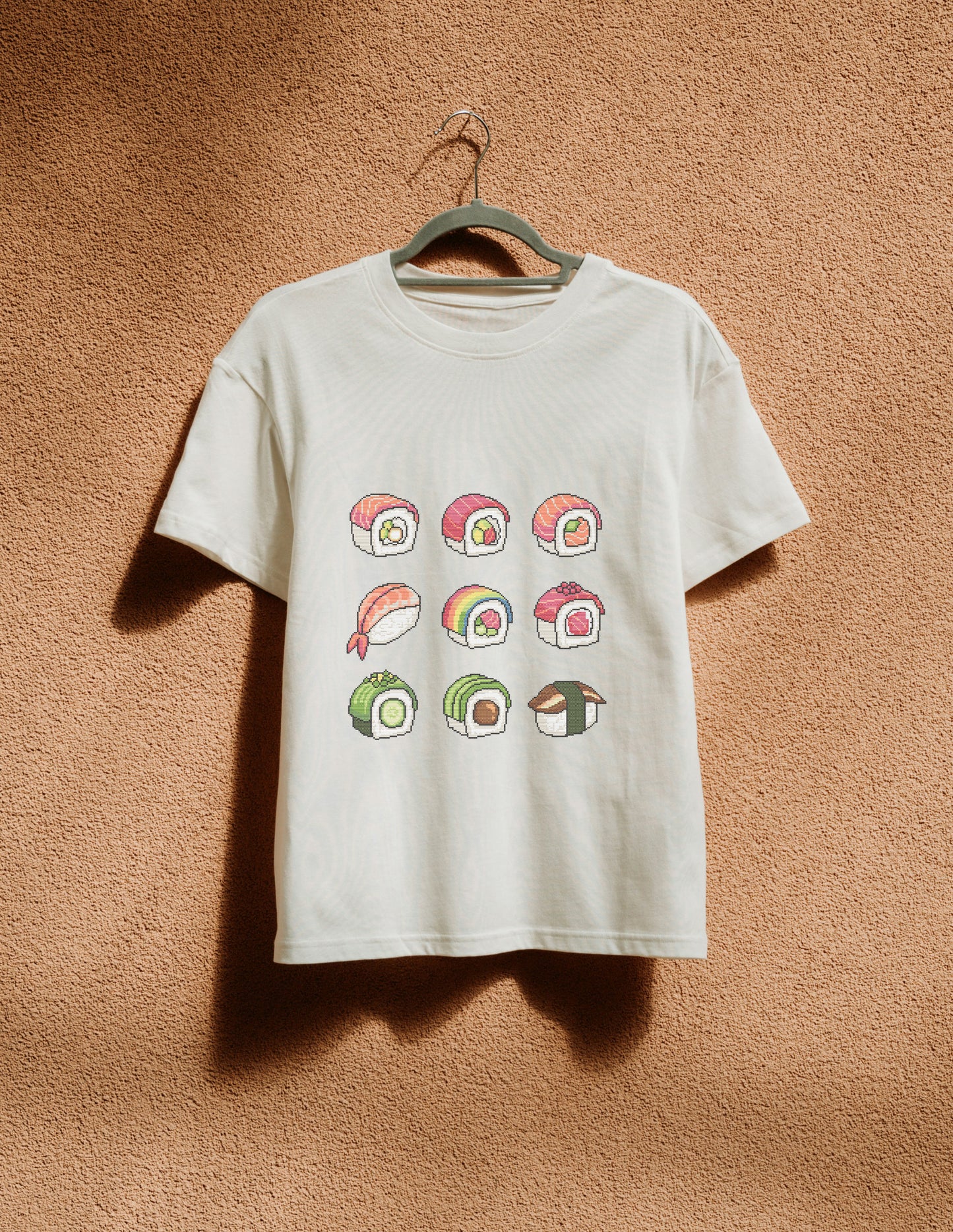White t-shirt with sushi graphic on a hanger against a textured brown wall