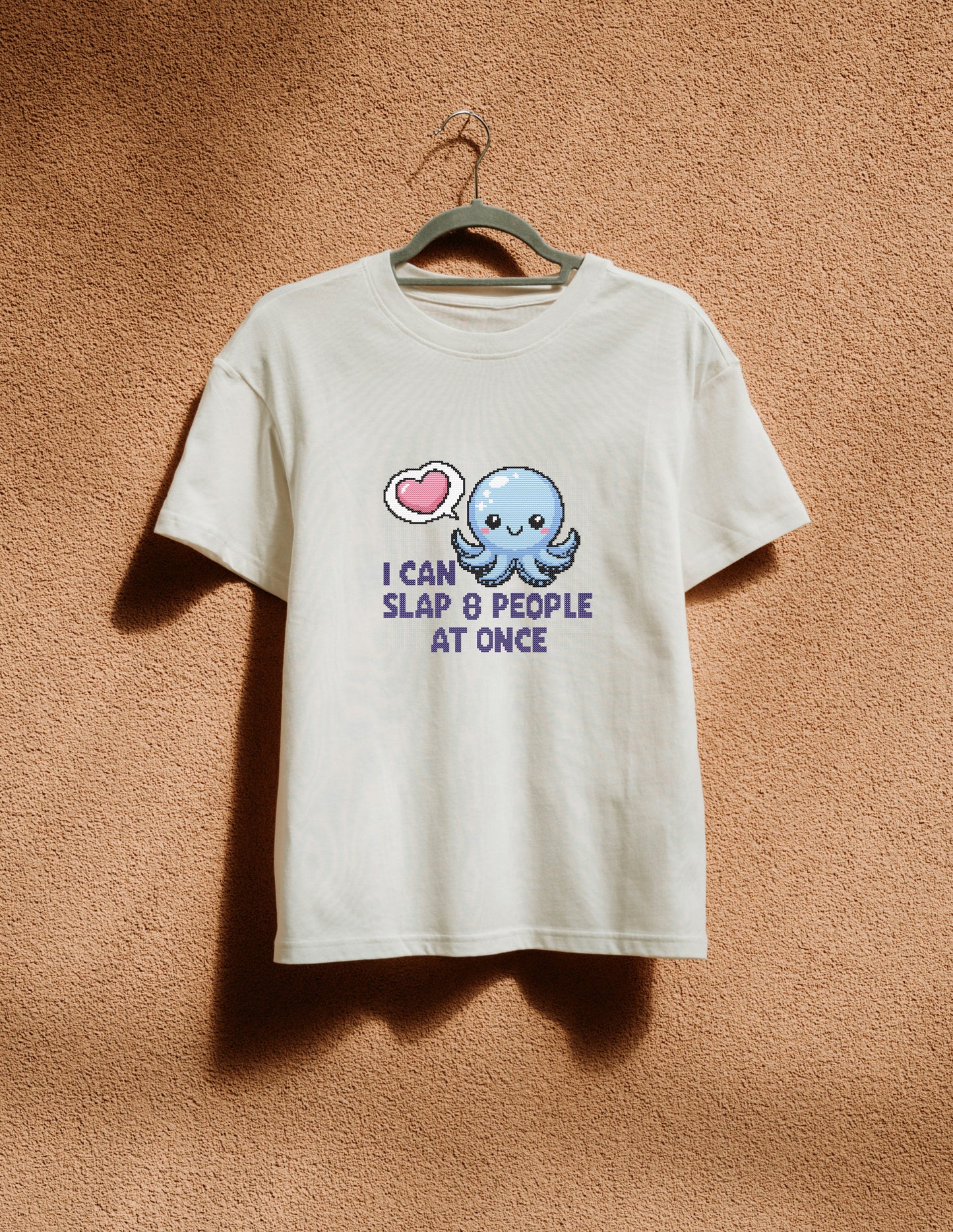 White t-shirt with a cartoon octopus design and text on a beige background