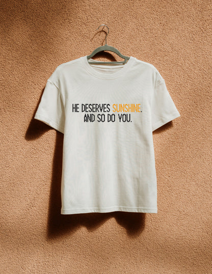 White t-shirt with text on a hanger against a brown textured wall