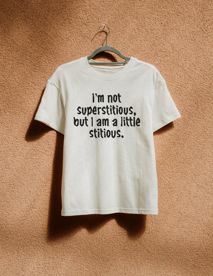 White t-shirt with humorous text on a hanger against a textured brown wall
