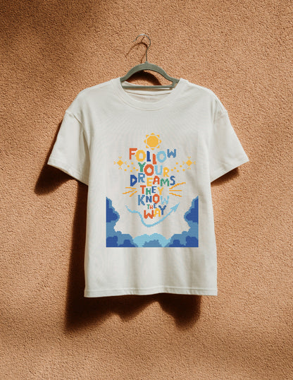 White t-shirt with colorful graphic and text on a hanger against a brown textured wall