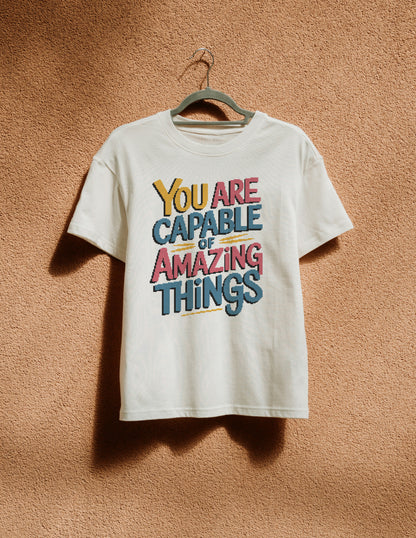 White t-shirt with motivational quote on a hanger against a textured brown wall
