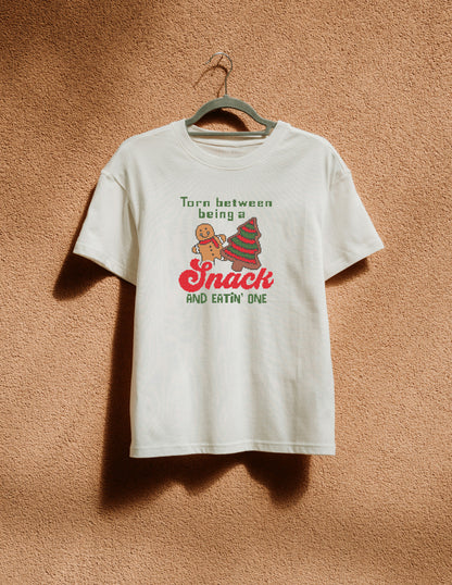 White t-shirt with Christmas-themed design on a hanger against a brown textured wall.