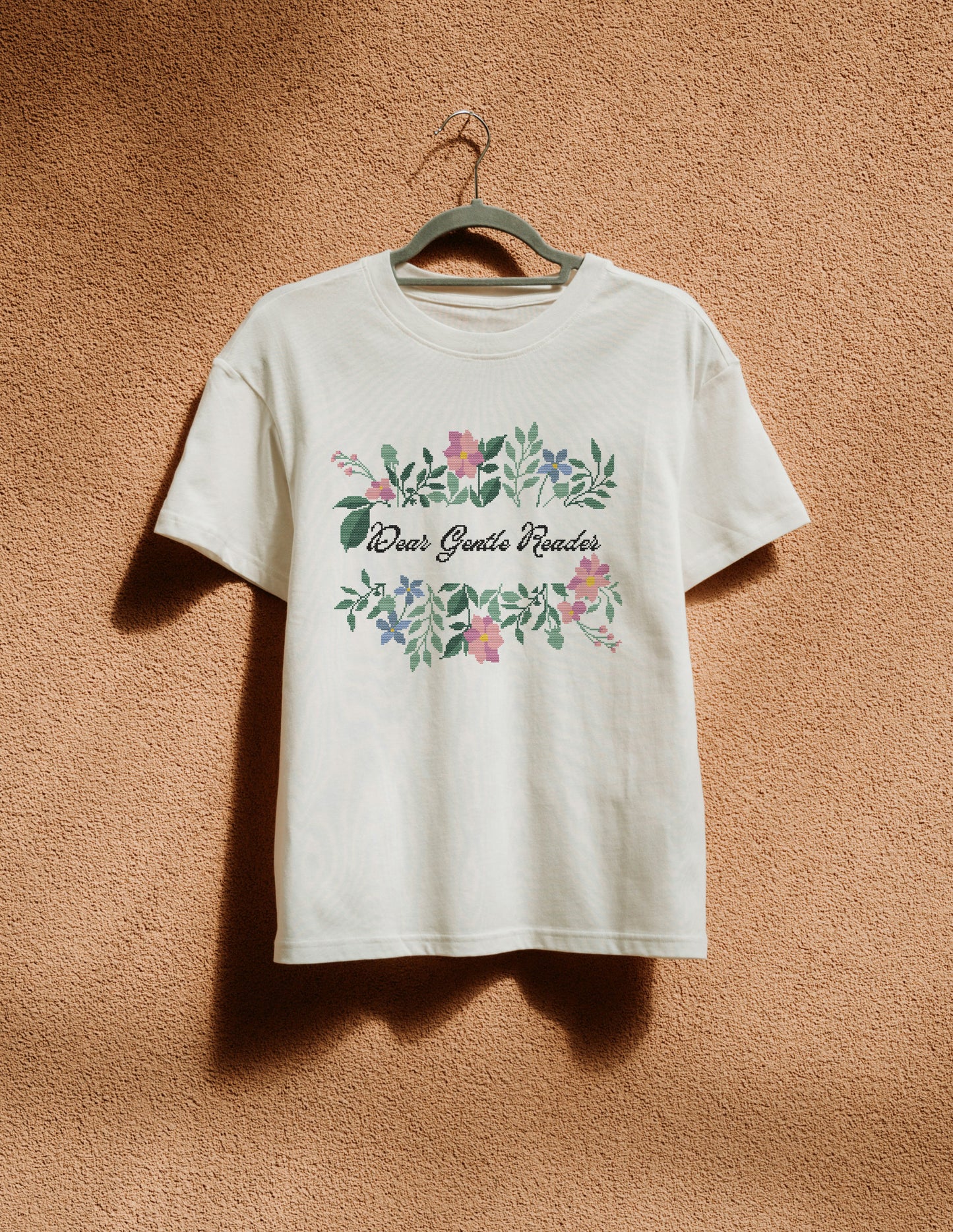 White t-shirt with floral design and text on a hanger against a brown background