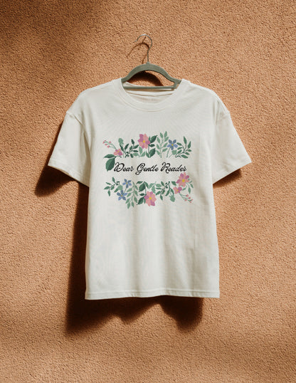 White t-shirt with floral design and text on a hanger against a brown background