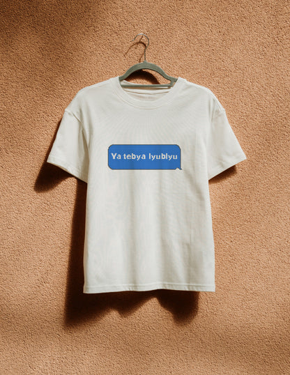 White t-shirt with a blue logo on a hanger against a brown wall