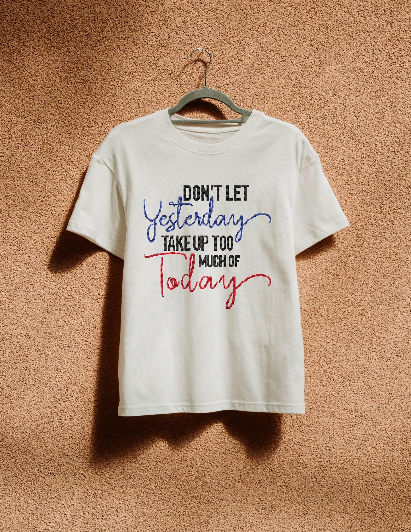 White t-shirt with motivational quote on a hanger against a brown background
