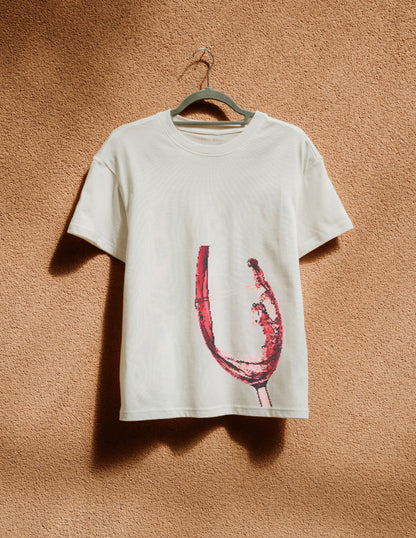 White t-shirt with a red graphic design on a hanger against a beige wall