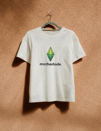 White t-shirt with 'motherlode' and logo on a hanger against a brown textured wall