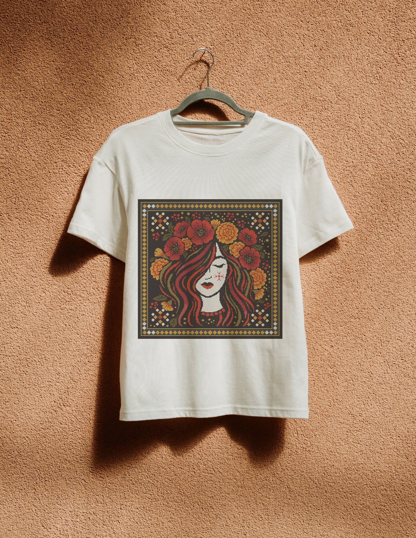 White t-shirt with a colorful graphic of a woman's face on a brown textured wall.