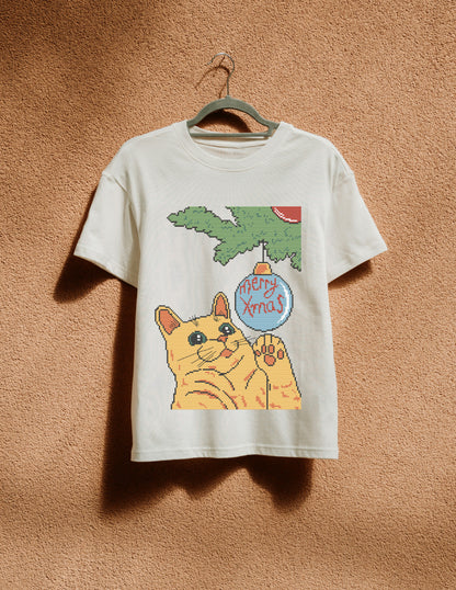 White t-shirt with a cat holding a 'Merry Xmas' ornament graphic on a brown background