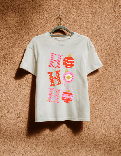 White t-shirt with 'Ho Ho Ho' design on a hanger against a brown textured wall