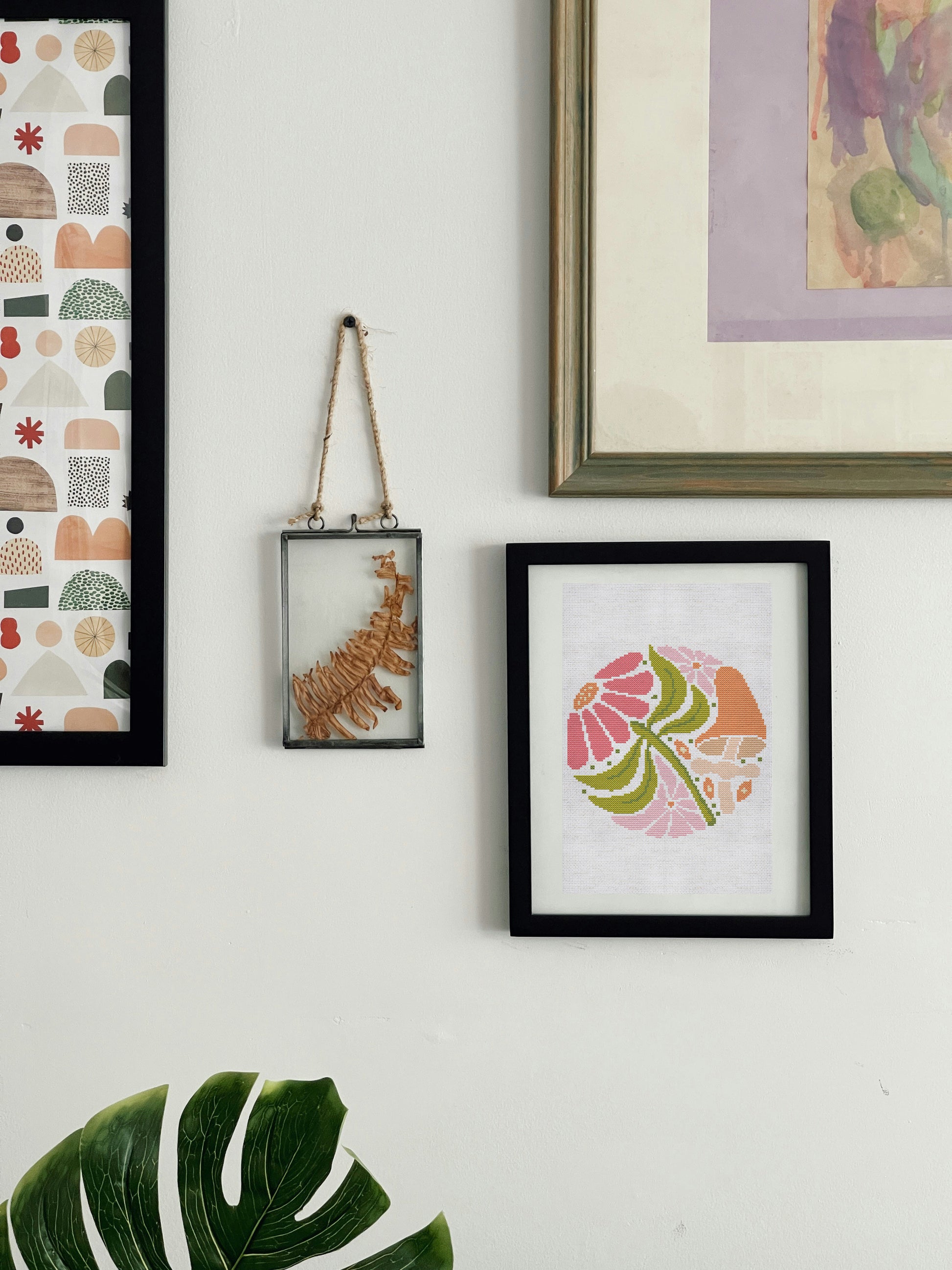Wall with framed artwork including a colorful abstract design, a leaf illustration, and a geometric pattern.